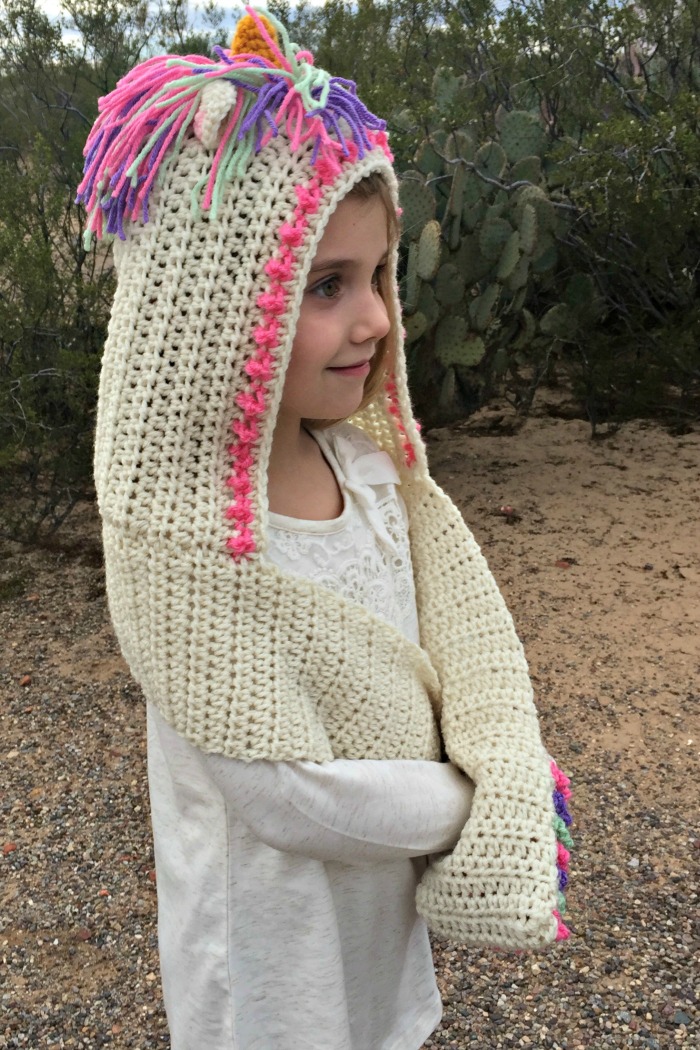 Unicorn Hooded Scarf With Pockets - These hooded free crochet scarf patterns are excellent alternatives to full-blown costumes when your kid is not into that kind of thing. #freecrochetscarfpatterns #crochetscarf 