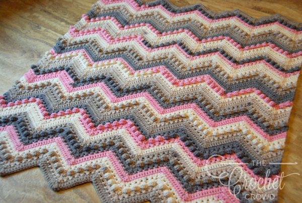 The Hugs and Kisses Crochet Baby Blanket laid out on the floor
