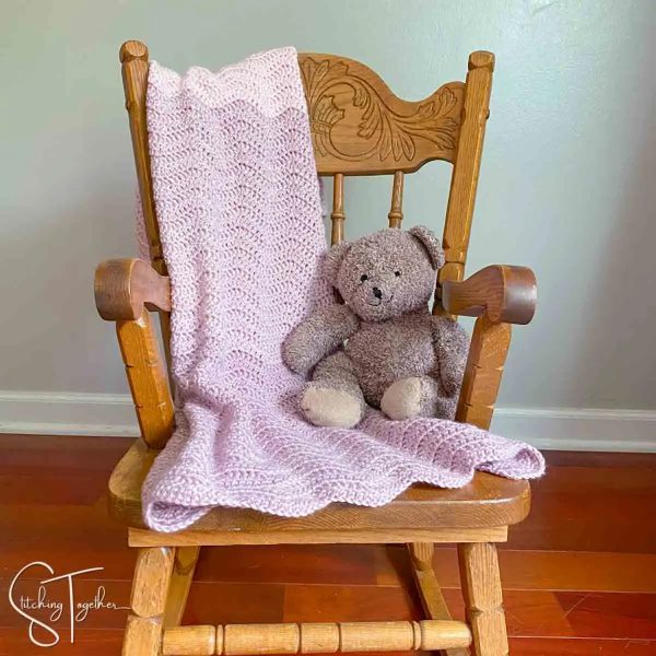 The Rapid Ripple Crochet Baby Blanket next to a stuffed teddy bear