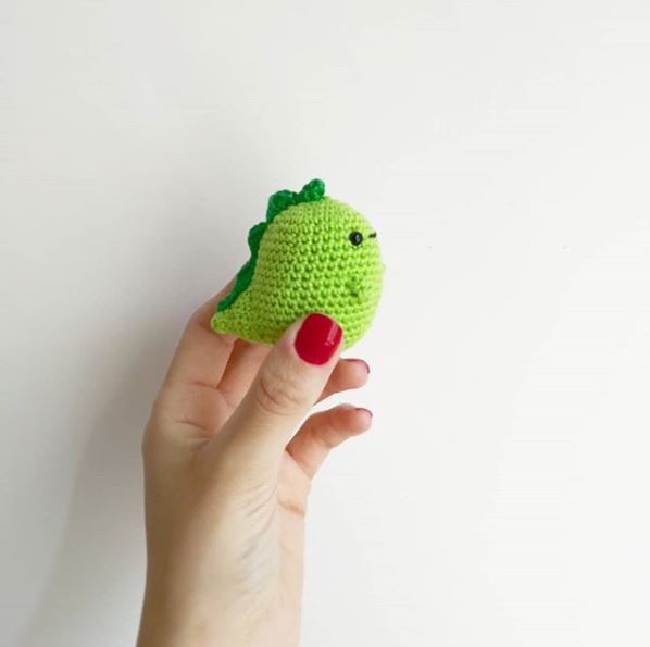 hand holding little crochet dinosaur