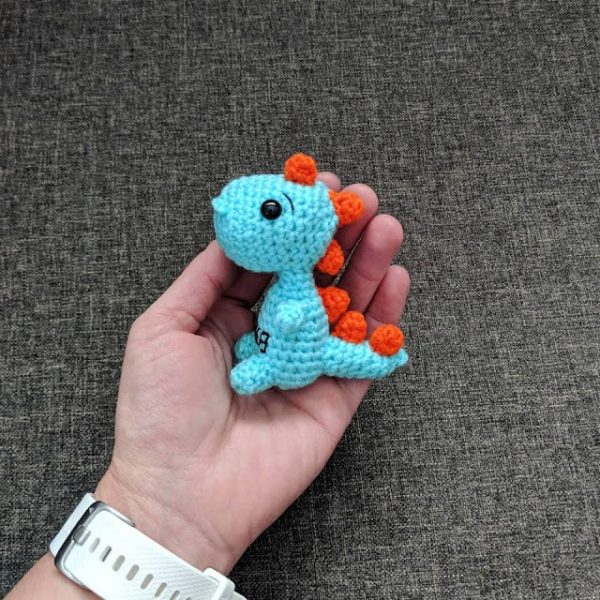 a person holding a crochet t-rex