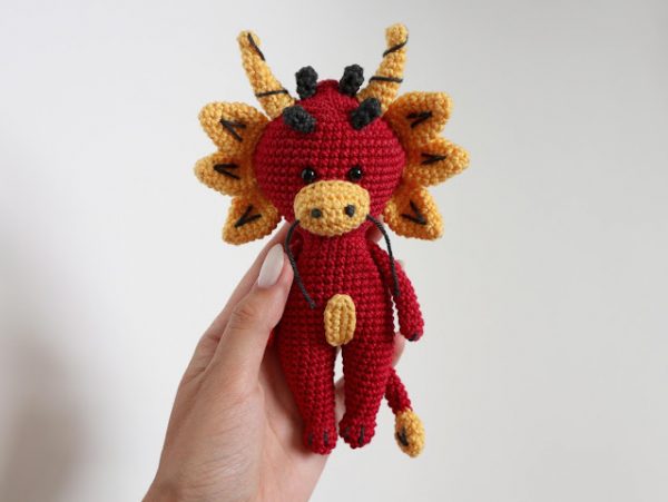 woman holding crochet dragon amigurumi based on the dragons in chinese zodiac